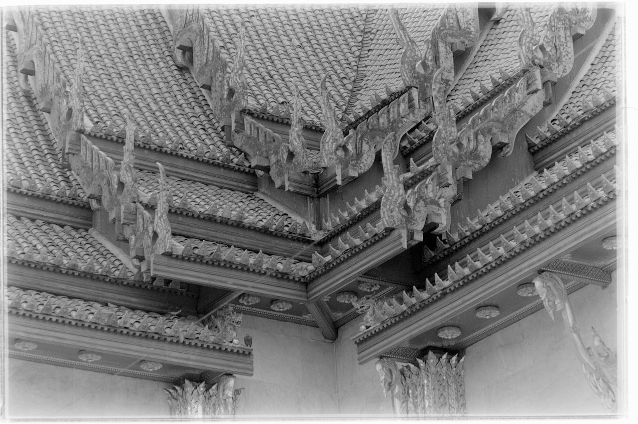 A temple roof intersection showing lots of tiles and Thai architecture.