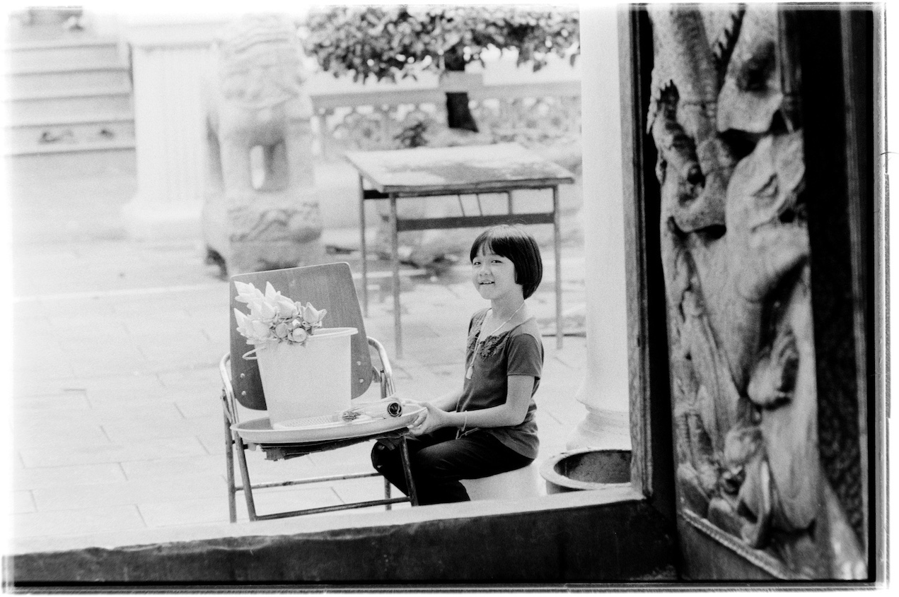 A girl selling bunches of flowers outside the temple entrance.
