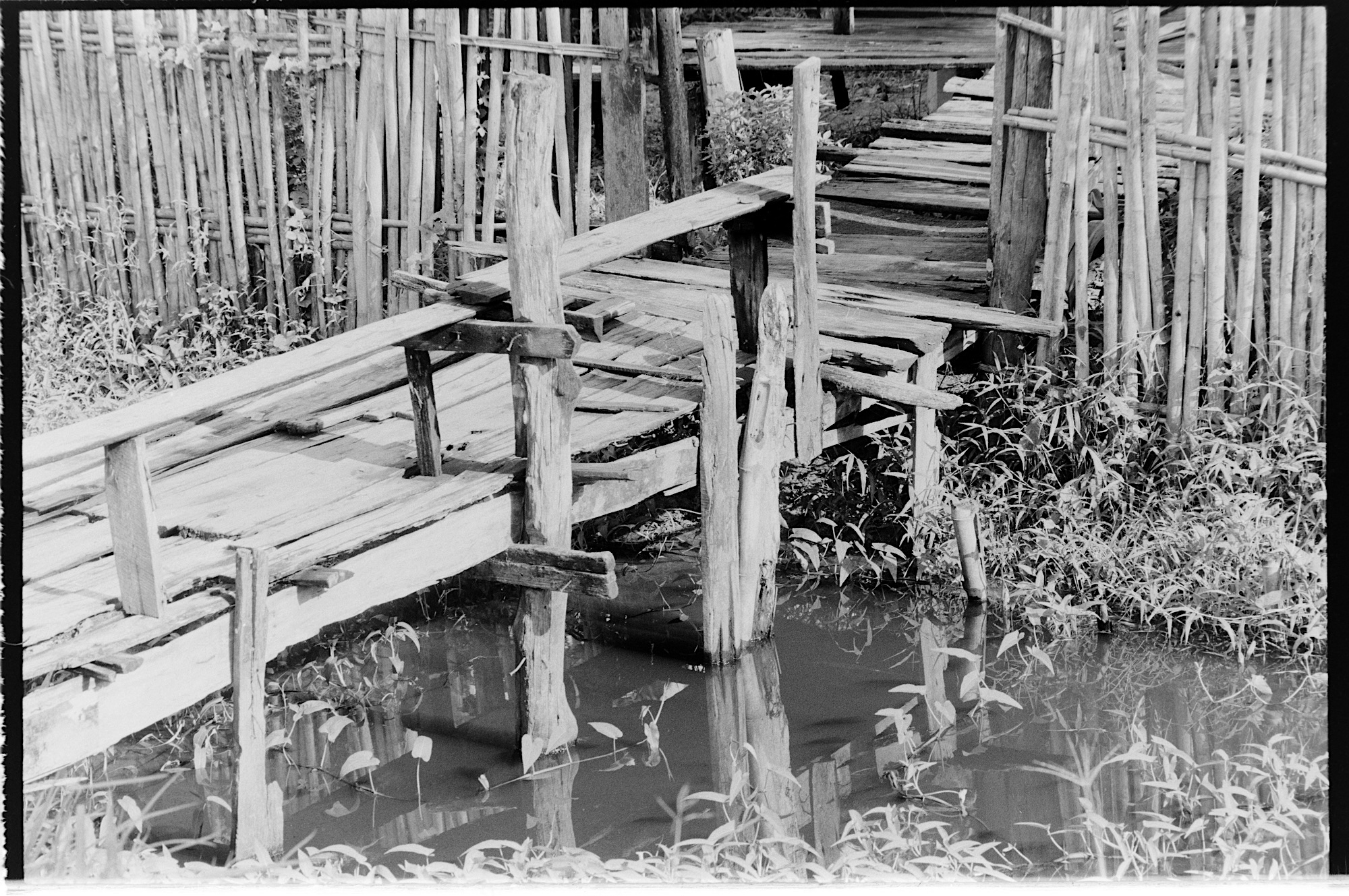 A wooden bridge across a ditch, as the entrance to a family home.